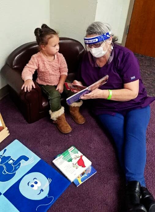 Woman reading book to young child at library