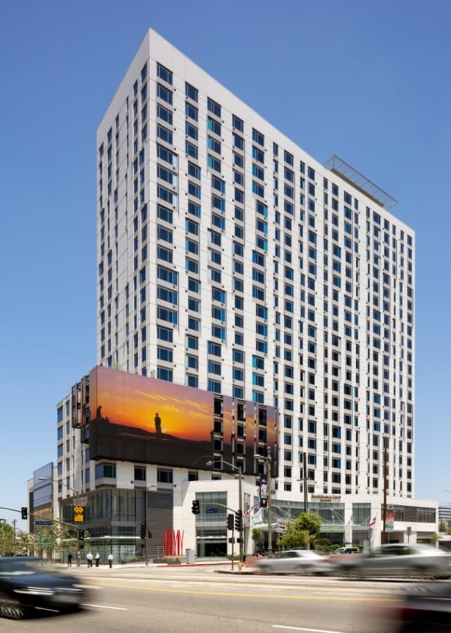 Modern high-rise building with billboard in urban setting.